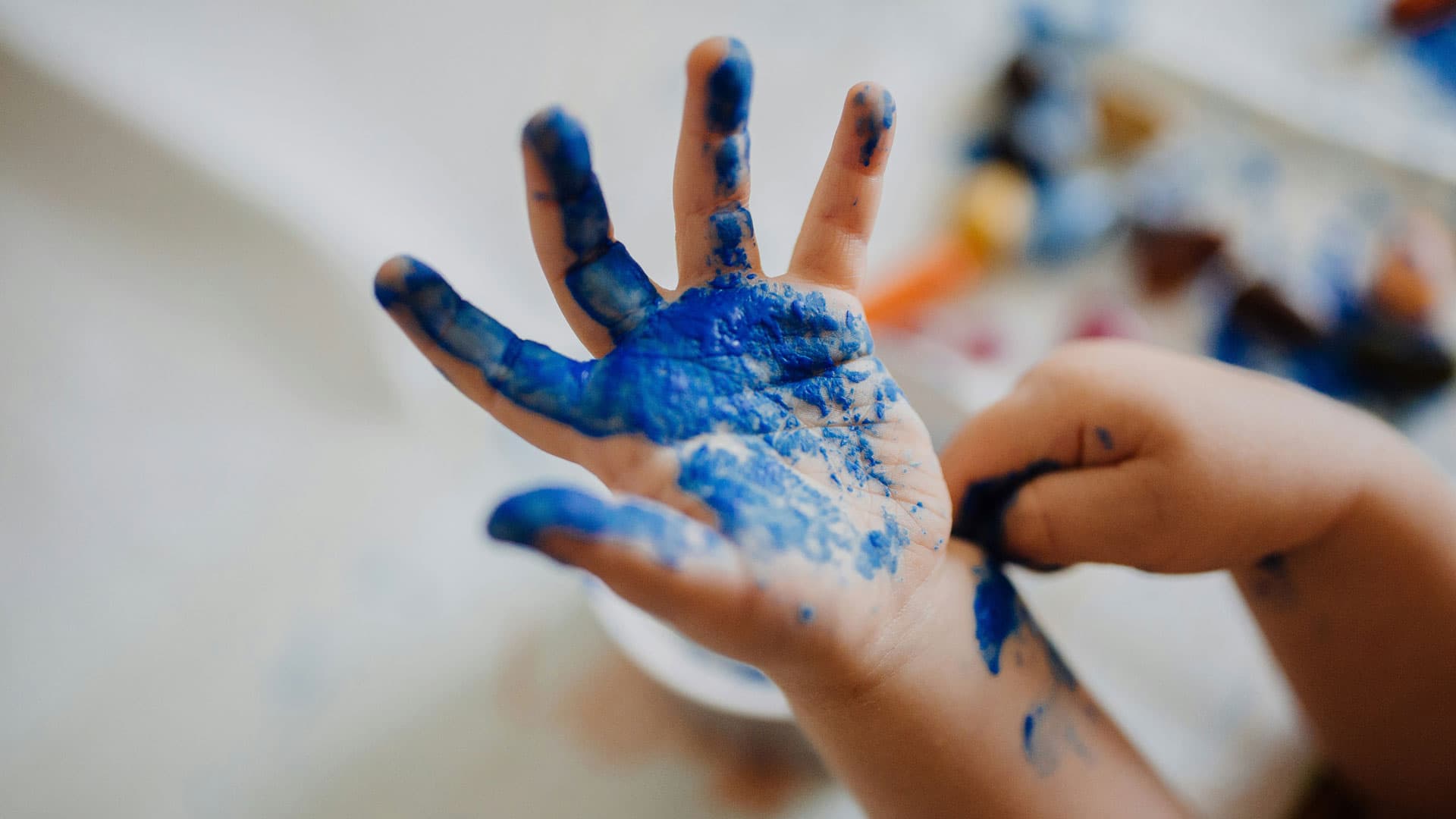 Kid painting its hands blue